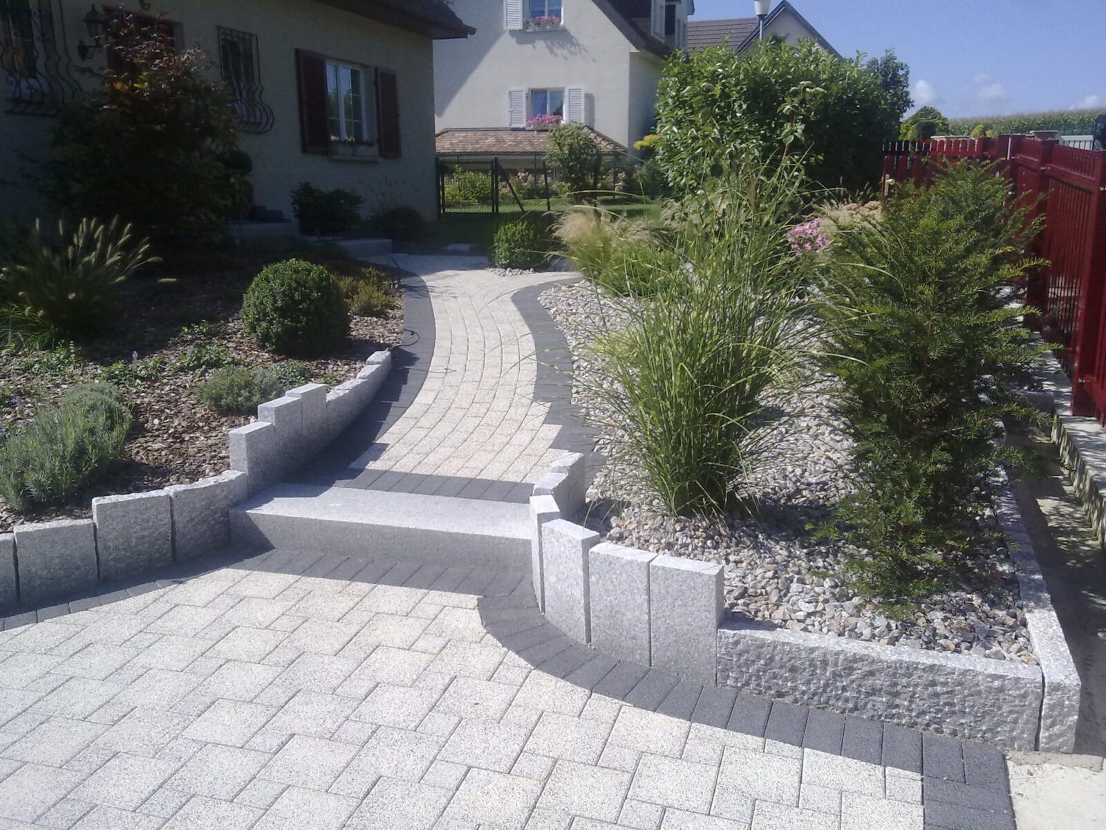 Allée pavée bordée de murets et de plantations